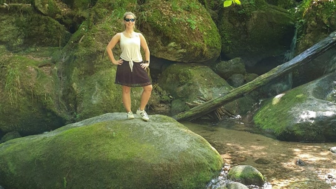 Lizzi steht selbstbewusst auf einem gewaltigen, bemoosten Stein. 