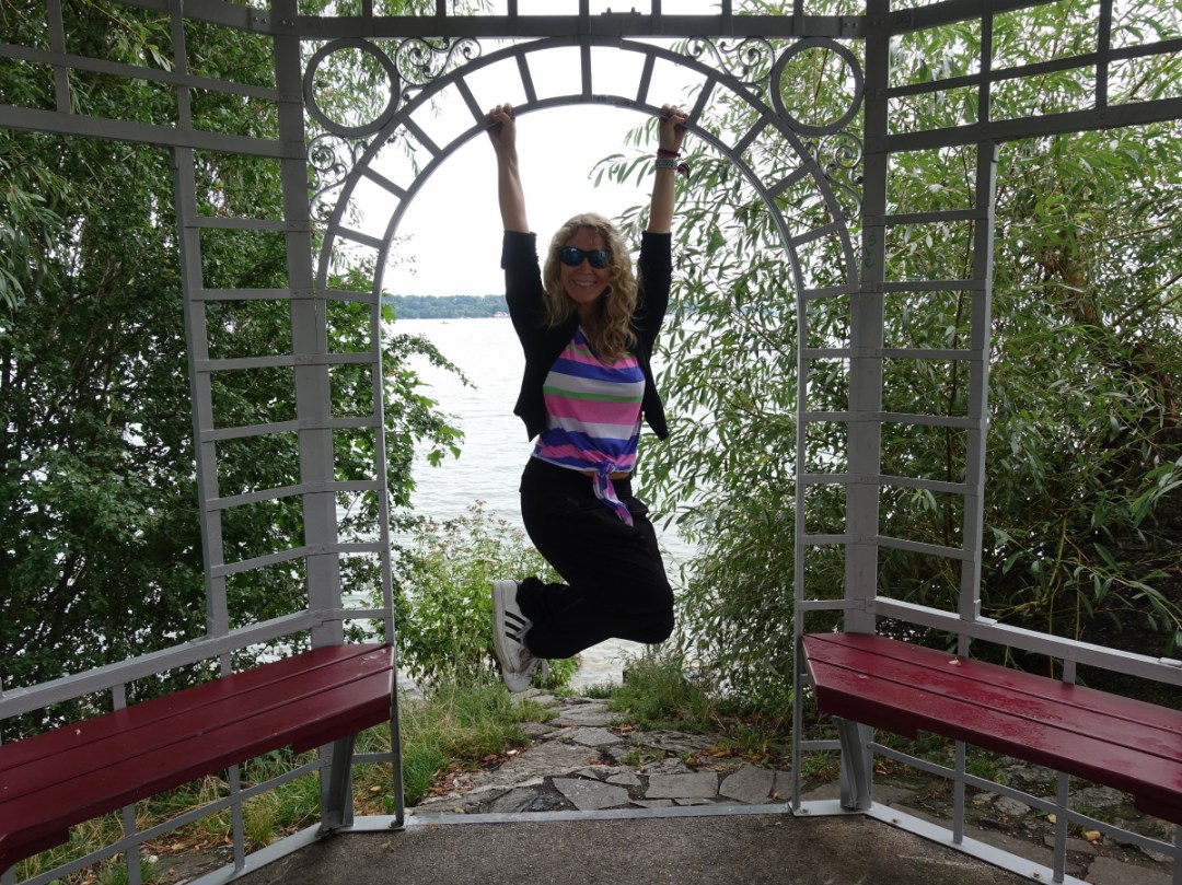 Lizzi hängt lachend von einer Stange eines kleinen Pavillons