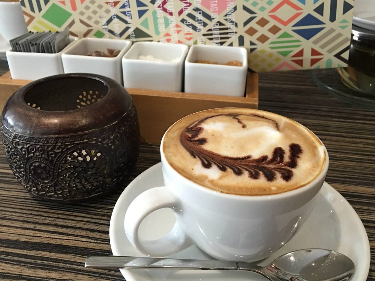 Eine Tasse Cappuccino mit bläterförmig verziertem Schaum.