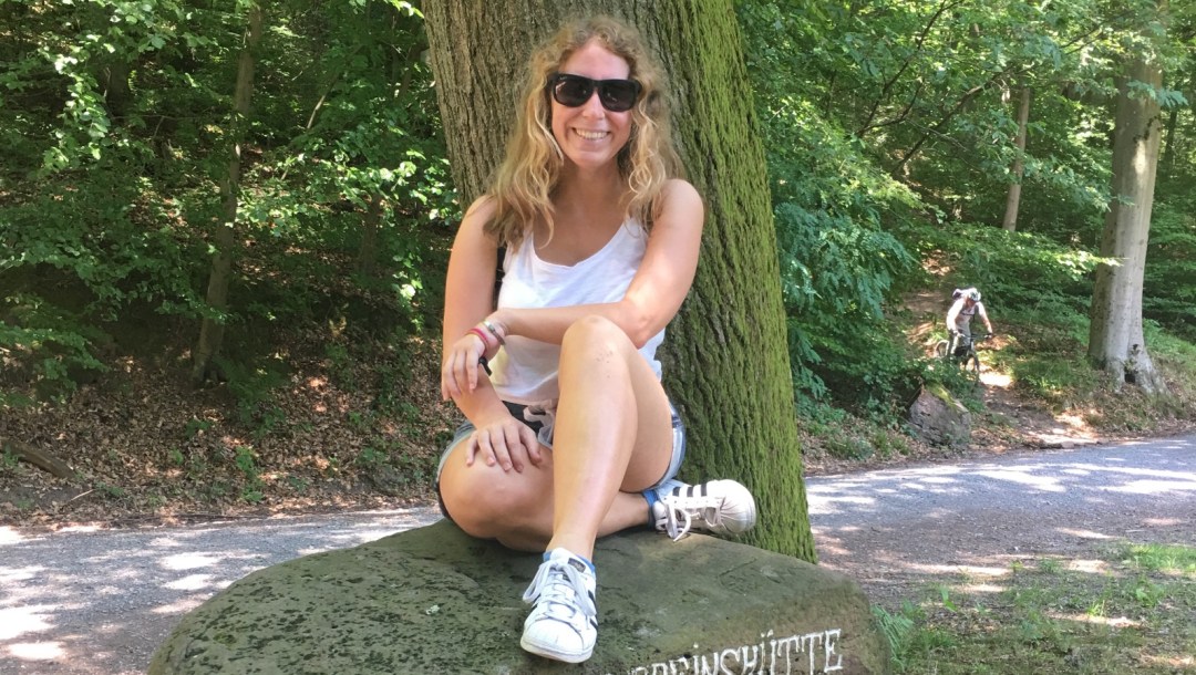 Lizzi sitzt lächelnd auf einem Stein.